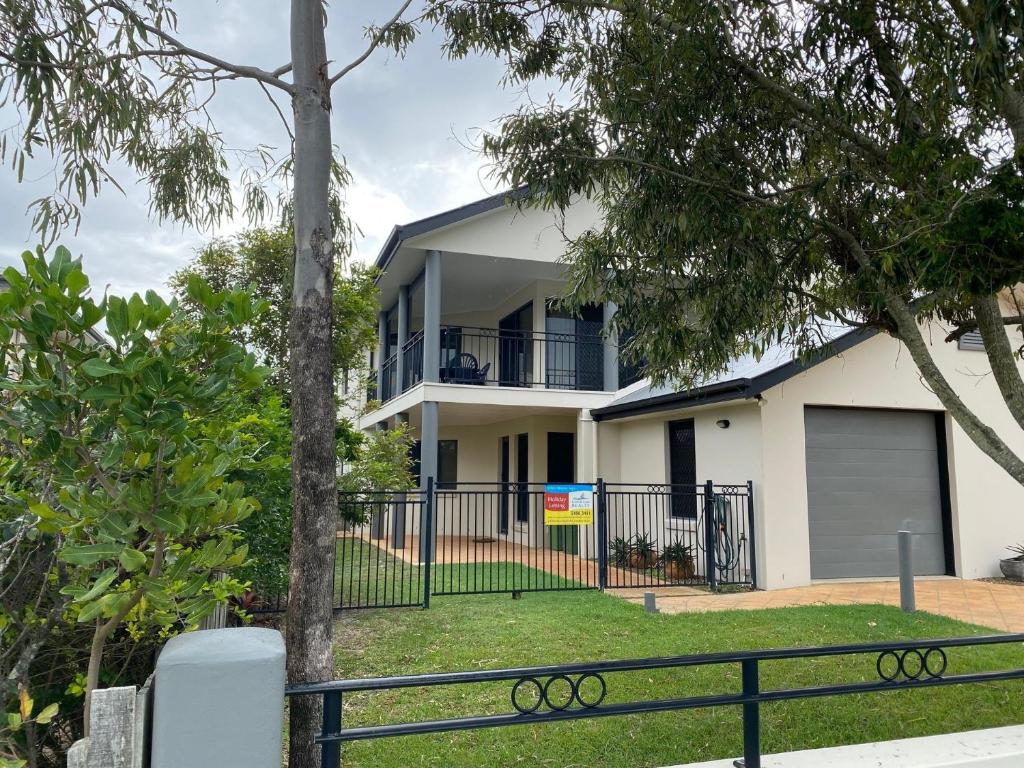 a white house with a black fence and trees at Indigo Place 1 Rainbow Beach in Rainbow Beach