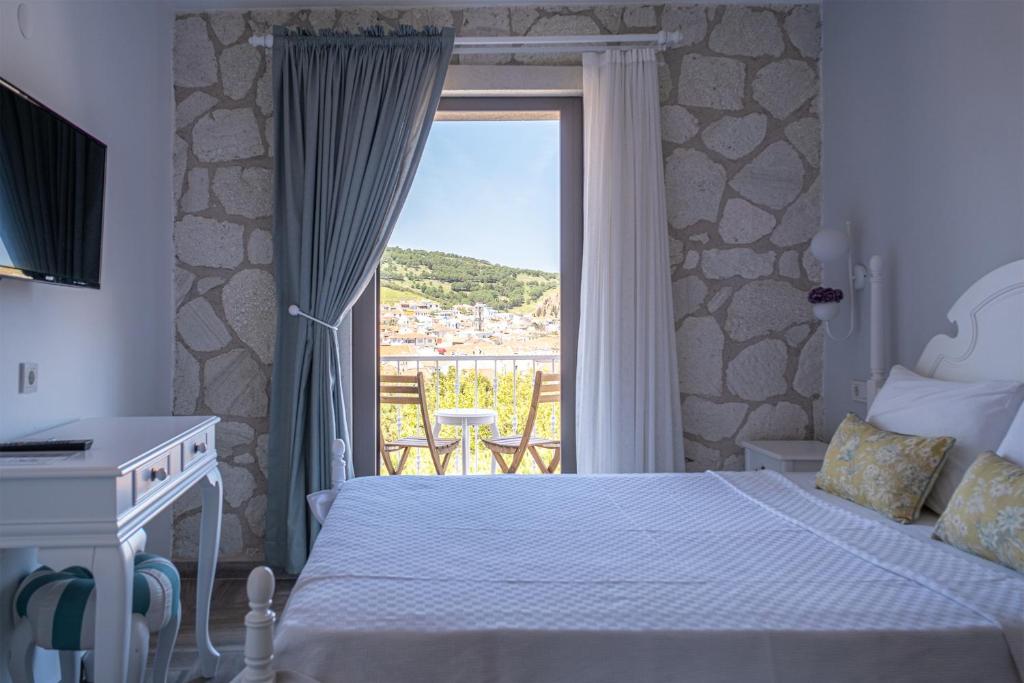 a bedroom with a bed and a balcony with a view at TaşAda Hotel - Special Class in Bozcaada