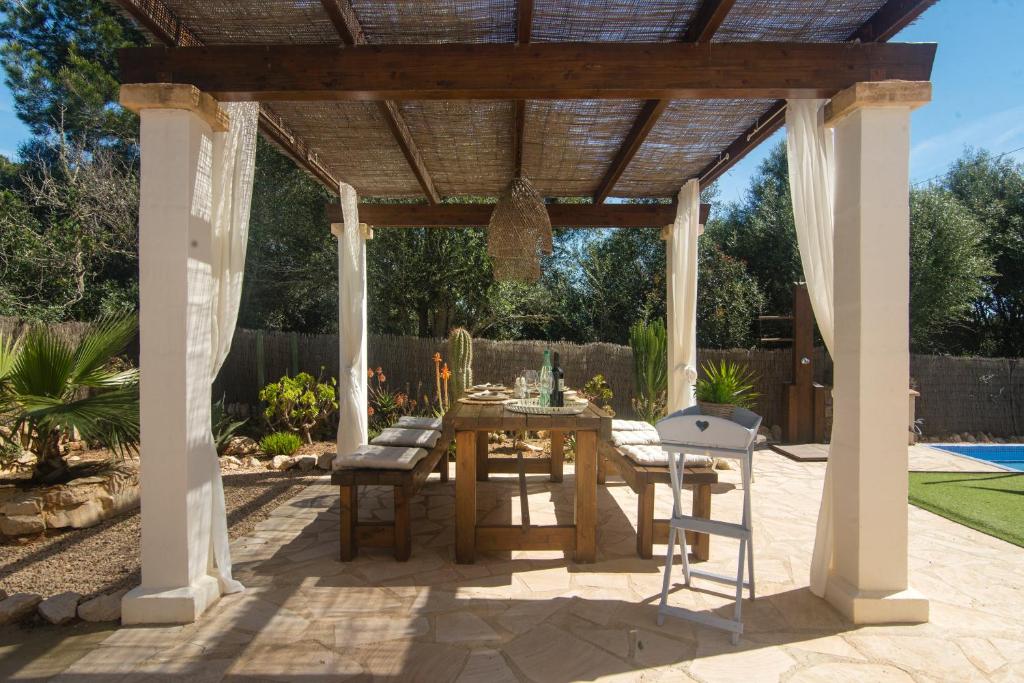 a patio with a table and chairs under a pergola at Casa Azul Stylish beach house for 4 adults and 1 child in Cala Llombards in Cala Llombards