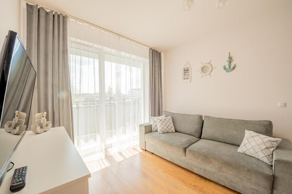 a living room with a couch and a large window at Harbor 9 Apartment in Kołobrzeg