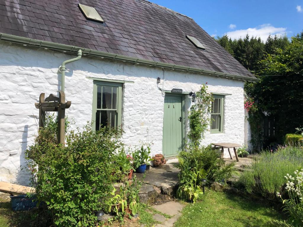 a white cottage with a green door in a garden at Traditional 18th Century Welsh Cottage in Llandovery