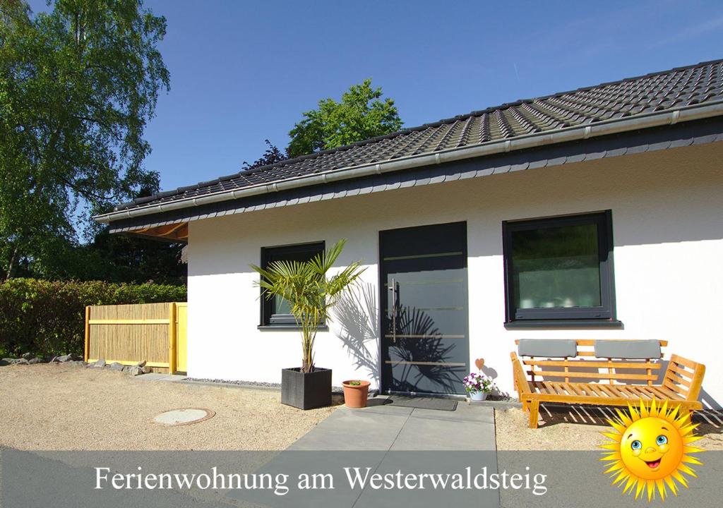 una casa con un banco con un sol sonriente en Ferienwohnung am Westerwaldsteig en Niederbuchenau