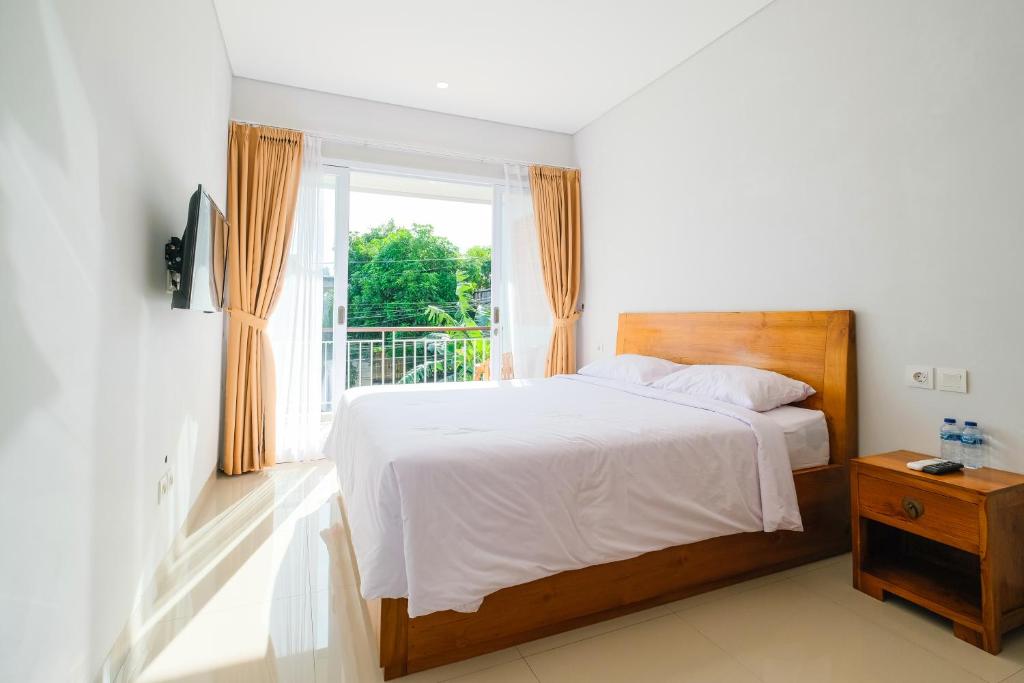 a bedroom with a large bed and a window at Dharma Guest House Seminyak RedPartner in Seminyak