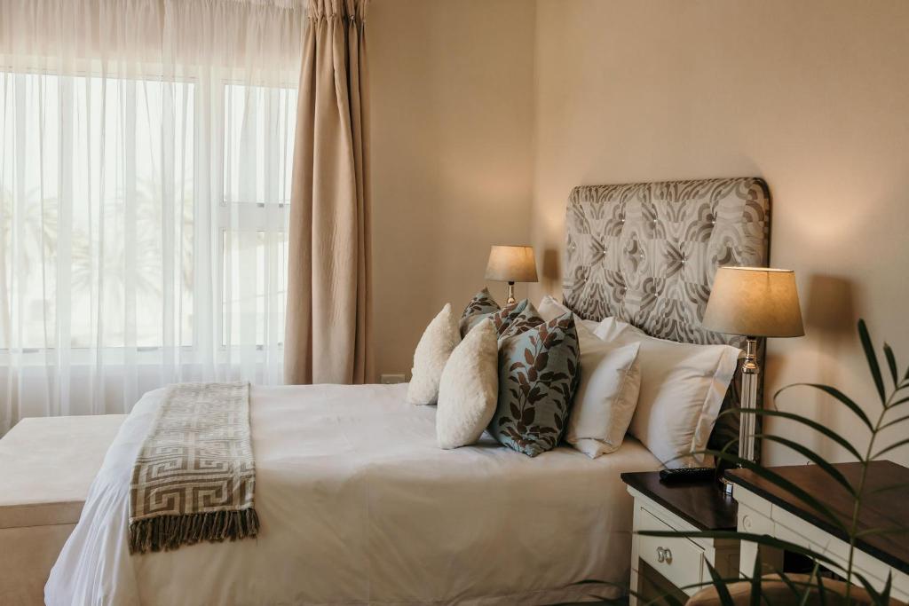 a bedroom with a bed with pillows and a window at Artemis Hotel Swakopmund in Swakopmund