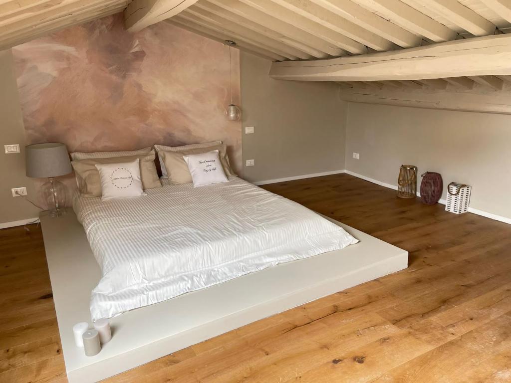 Cama blanca grande en habitación con suelo de madera en Alberto e Costanza Suite, en Lucca