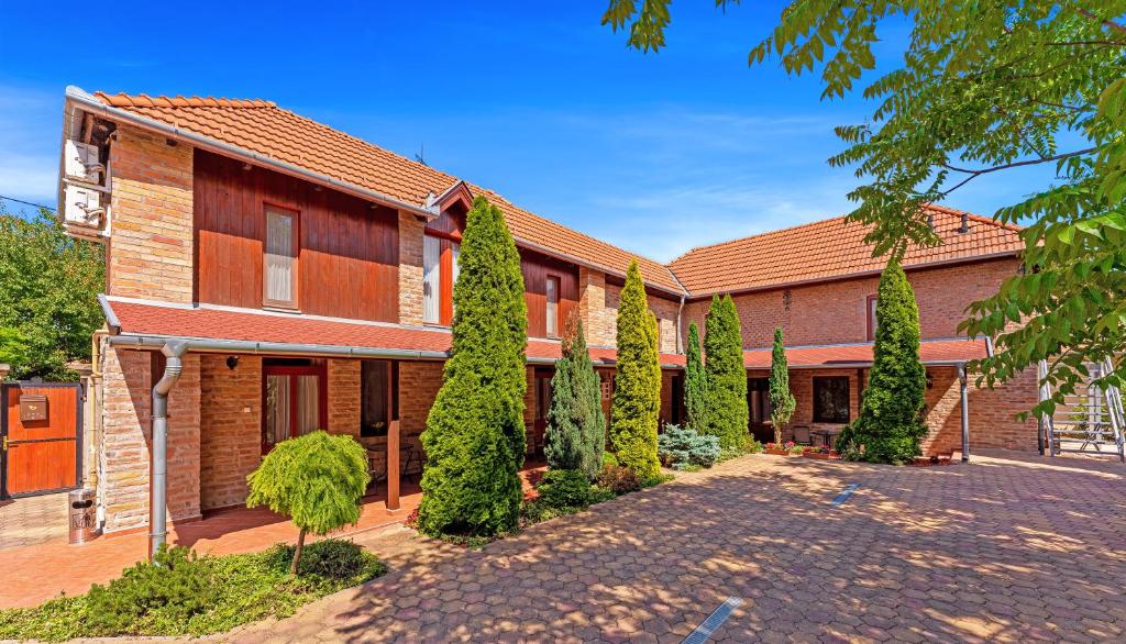 a brick building with trees in front of it at Varázskő Apartman in Gyula