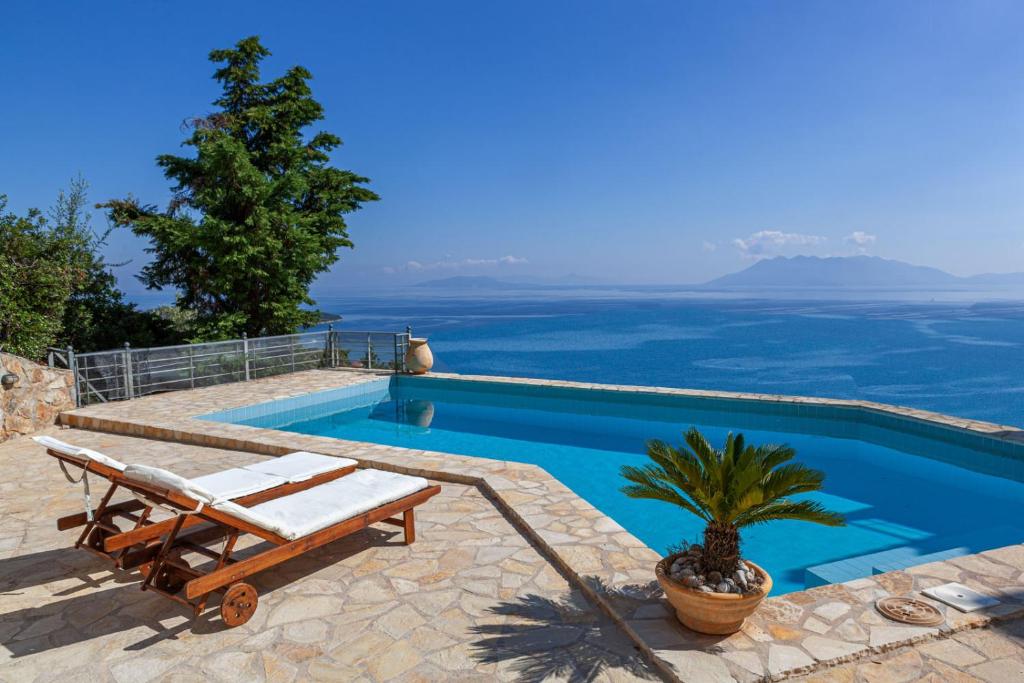 una piscina con un banco y una palmera en Epidavros Land villa Antigoni, en Palaia Epidavros