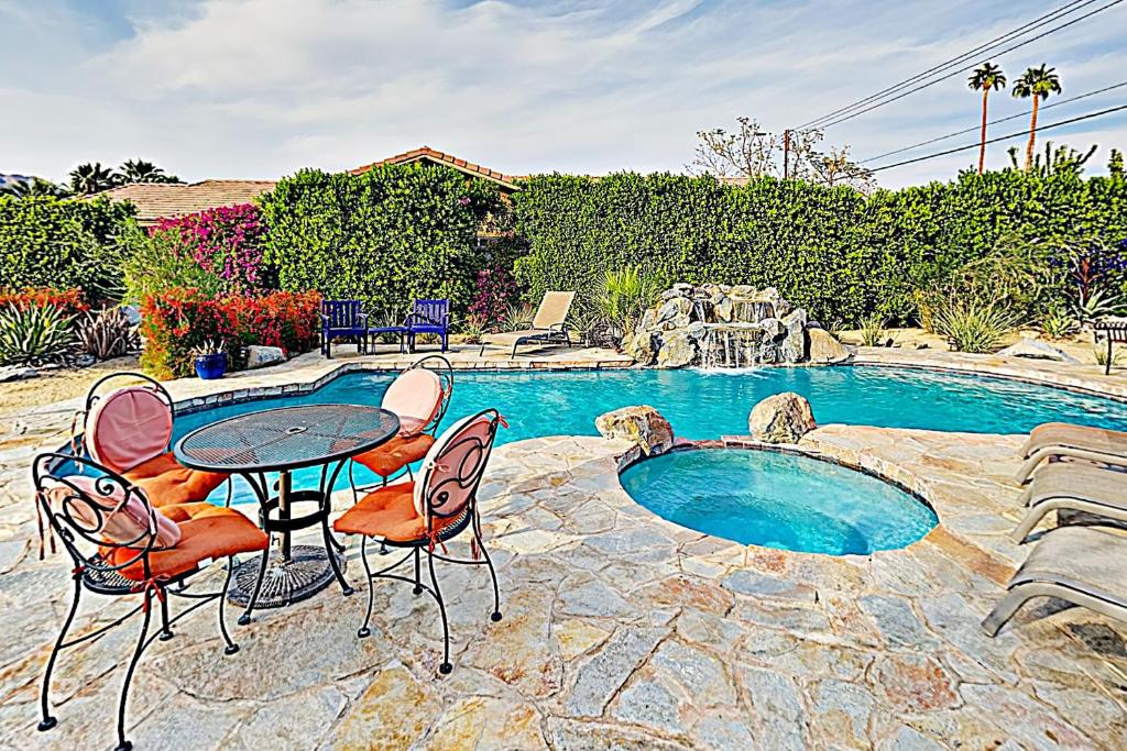 Un patio con mesa y sillas junto a una piscina. en Avenida Mendoza Escape Permit# 67701, en La Quinta