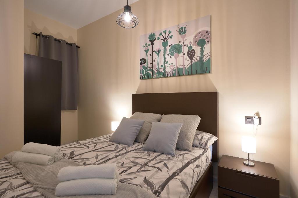 1 dormitorio con 1 cama y una pintura en la pared en Apartamentos Tejares de Triana 16B, en Sevilla