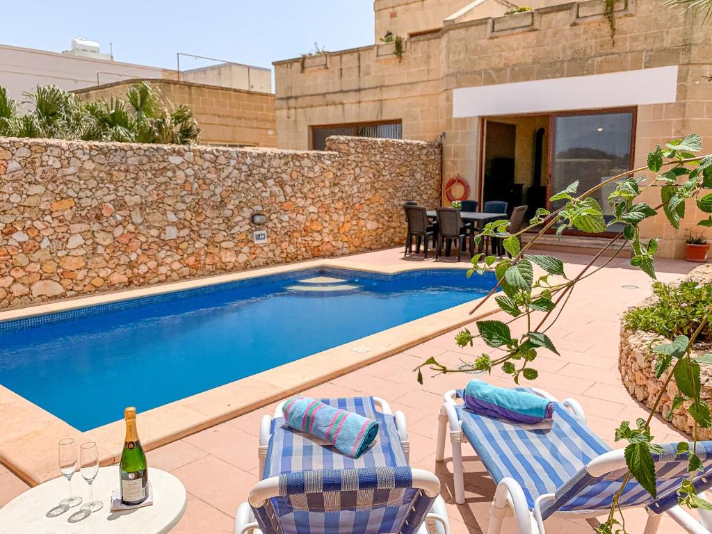 - une piscine avec 2 chaises et une bouteille de vin dans l'établissement Villa Fieldend - Gozo Holiday Home, à L-Għarb