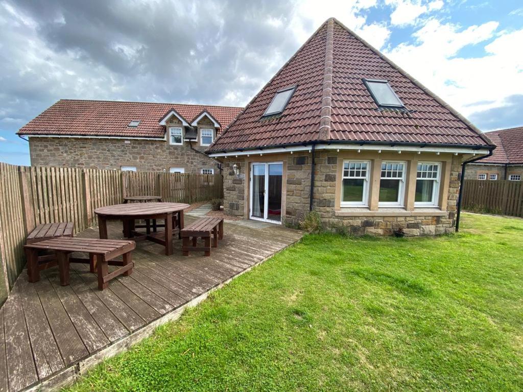 a patio with a table and benches in front of a house at The Roundal in Crail