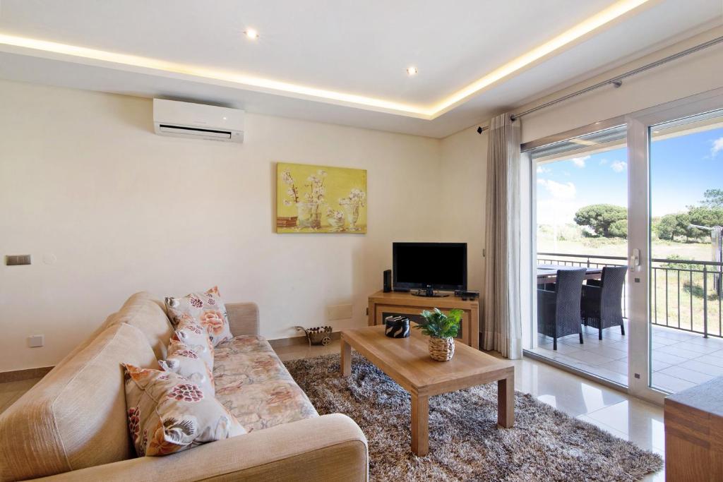 a living room with a couch and a tv at Varandas do Sol - Olhos de Água in Albufeira