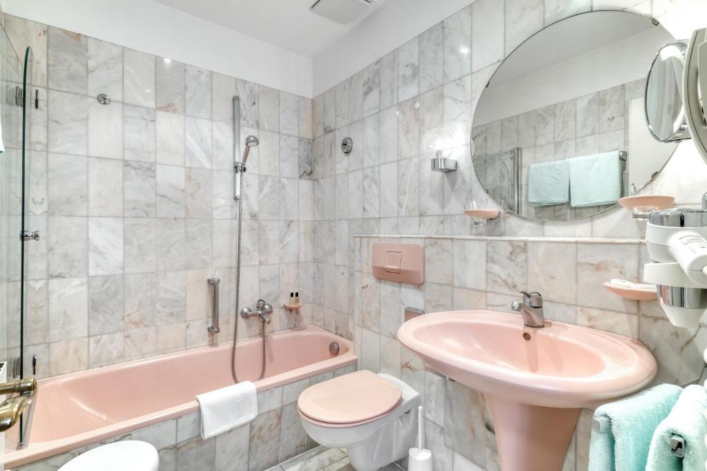 a bathroom with a pink tub and a sink and a toilet at Hotel Eisenhut in Rothenburg ob der Tauber