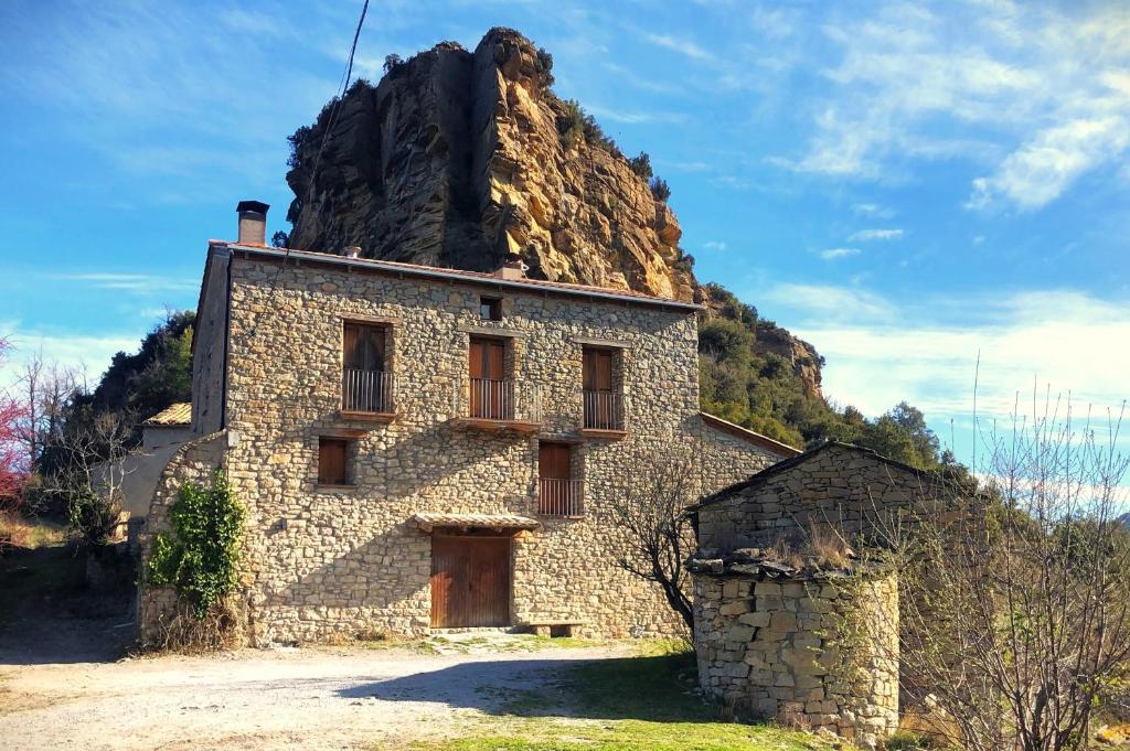 una vieja casa de piedra frente a una montaña en Masia la Oliva en Coll de Nargó