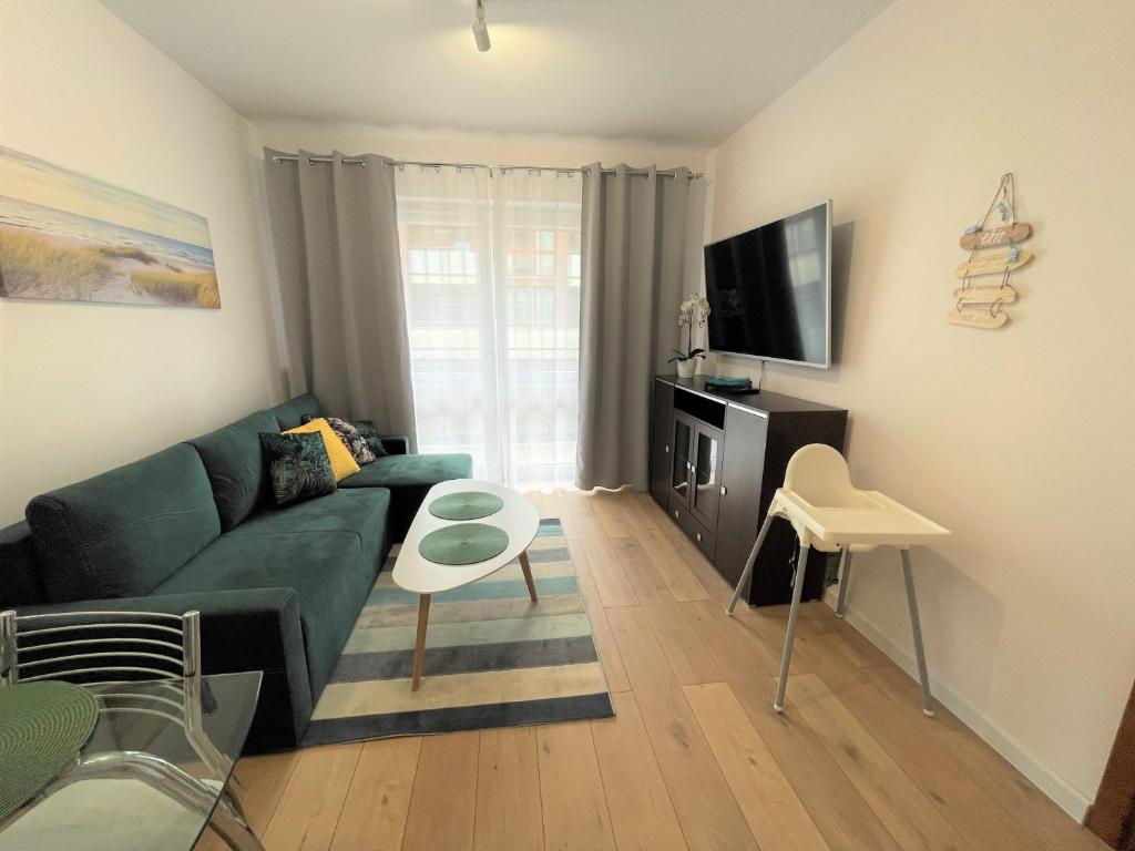 salon z zieloną kanapą i telewizorem w obiekcie AL-DOM Apartament Ogrodowa Bocianie Gniazdo z garażem w Kołobrzegu