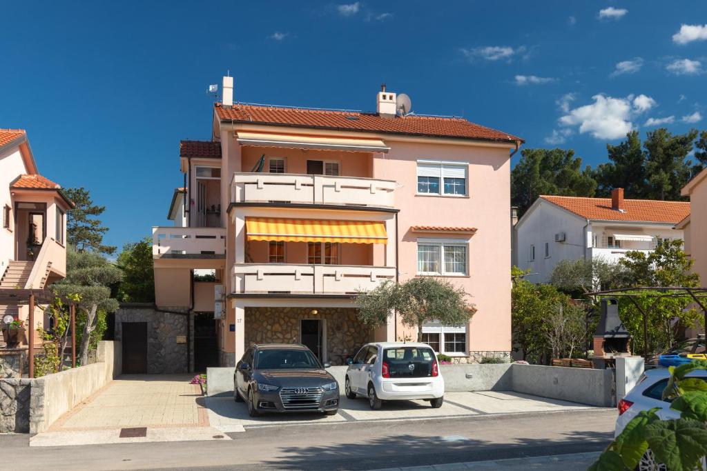 dwa samochody zaparkowane na parkingu przed budynkiem w obiekcie Apartman Ruza w Krku