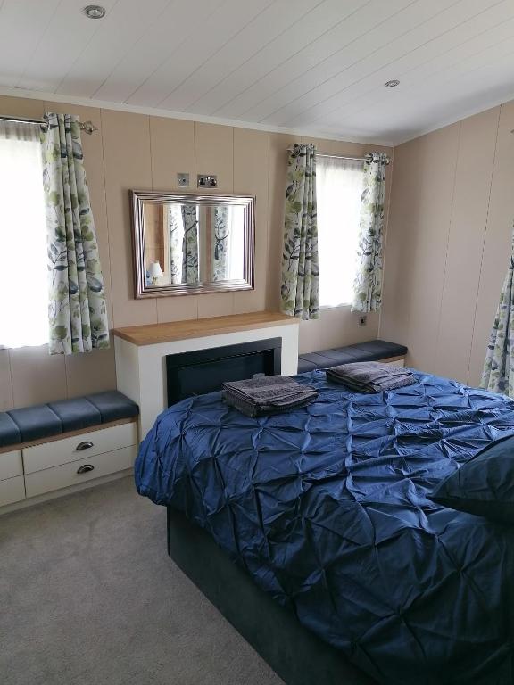 a bedroom with a bed and a mirror and windows at STUNNING, PEACEFUL LODGE on edge of New Forest and 800m from sea ENTERTAINMENT and LEISURE PASSES INCLUDED in Milford on Sea