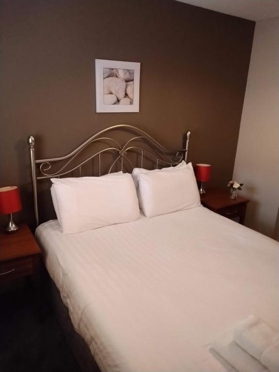 a bedroom with a bed with white sheets and two lamps at Victoria Cloisters Apartments in York