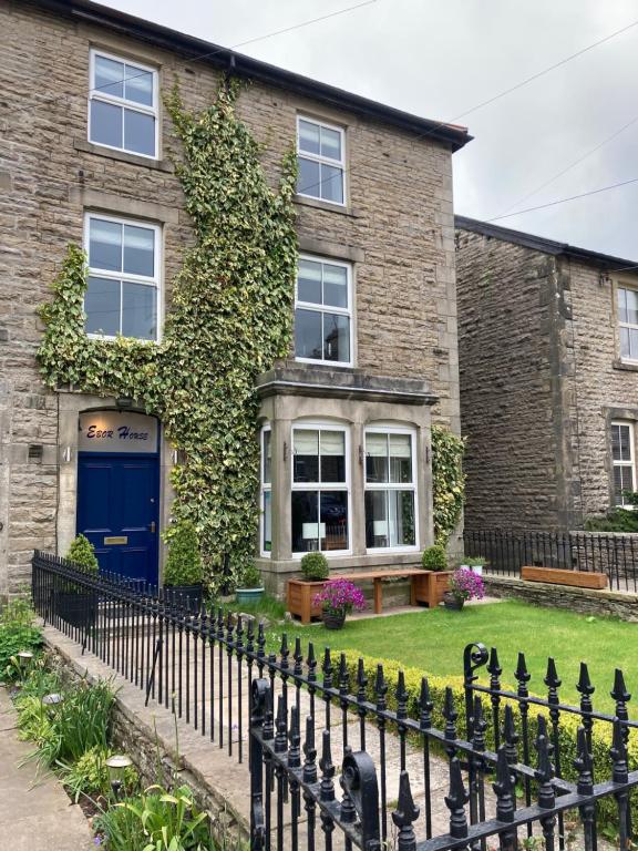 a brick house with a blue door and ivy at Ebor House in Hawes