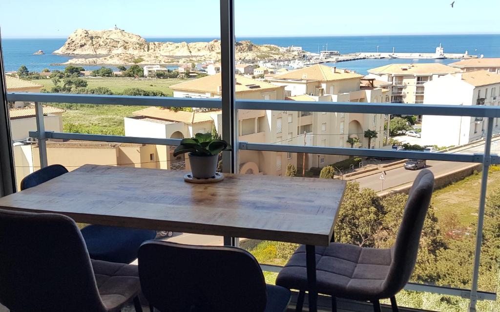 una mesa en un balcón con vistas al océano en Très Beau Duplex vue panoramique Mer, Proche Plage en LʼÎle-Rousse