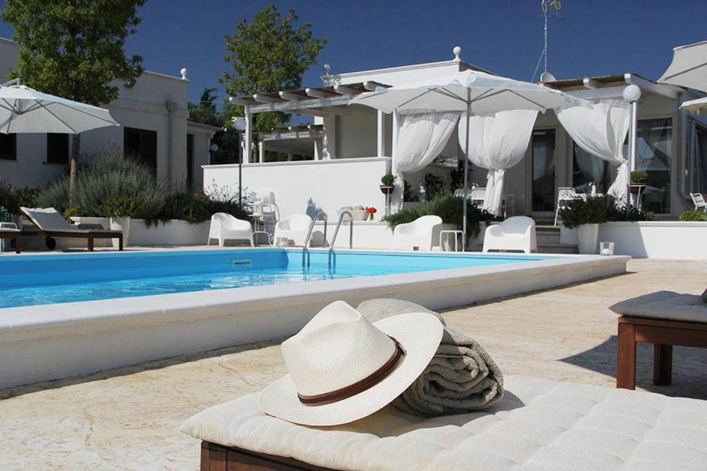 un sombrero sentado en un banco junto a una piscina en Relais Lali' en Mottola