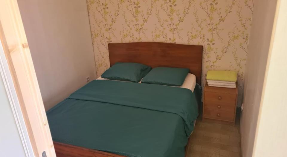 een bed met 2 groene kussens en een houten hoofdeinde bij Le domaine du bengal 2 in Veuil