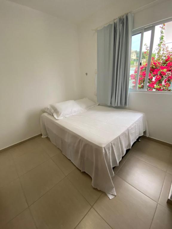 a bed in a white room with a window at Casa em Condomínio, Aquiraz - CE in Aquiraz