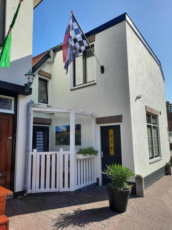 een wit huis met een vlag ervoor bij Zeelucht in Zandvoort