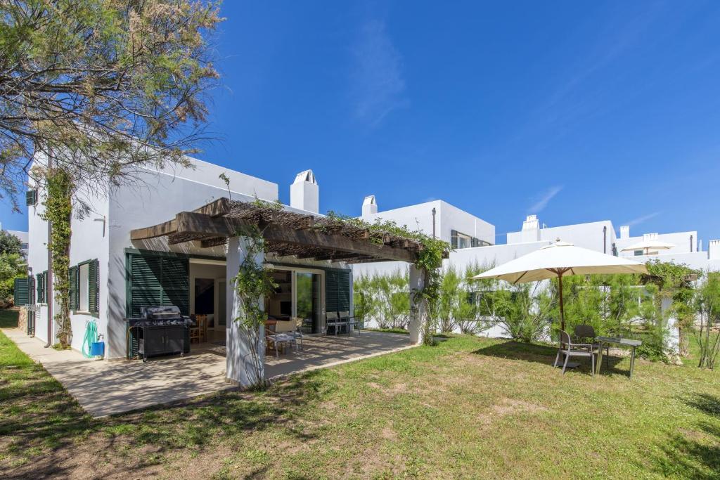 a white building with a patio and an umbrella at Biniancolla Ginesta in Biniancolla