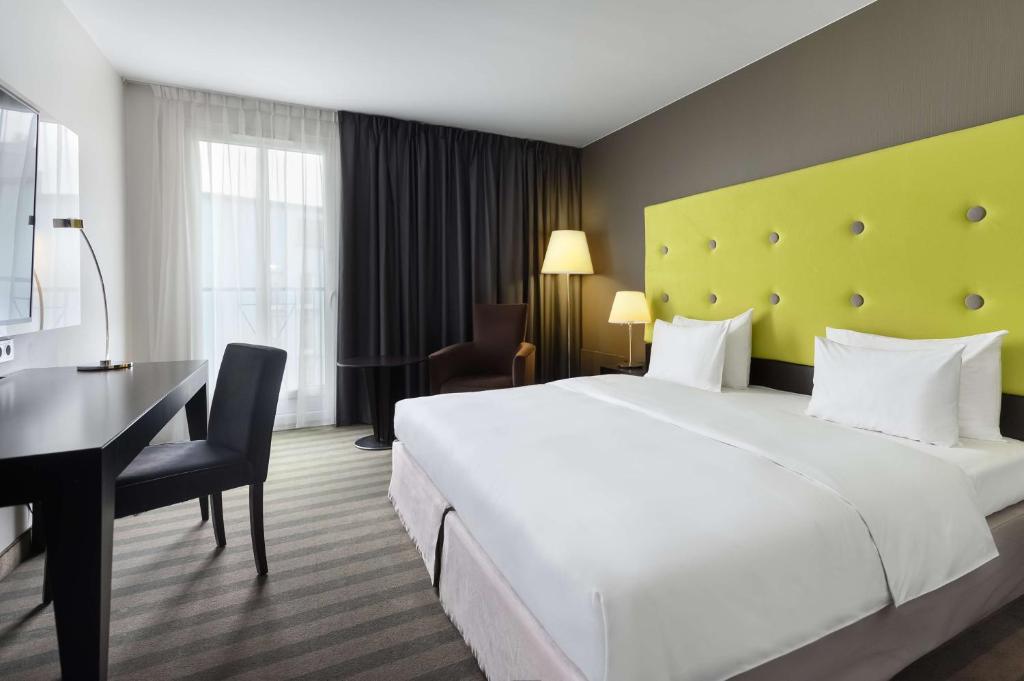 a hotel room with a bed, chair, table and lamps at Radisson Blu Sobieski in Warsaw