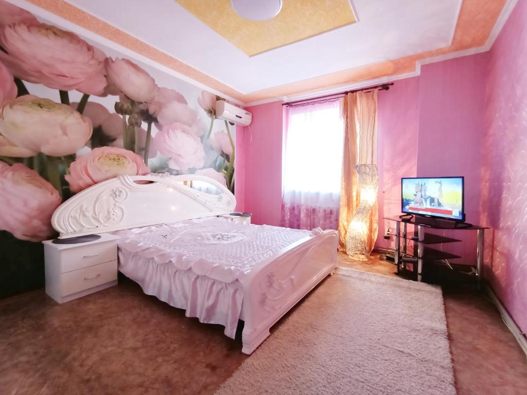 een slaapkamer met roze muren en een bed en een televisie bij Шевченко 1 in Kropyvnytsky