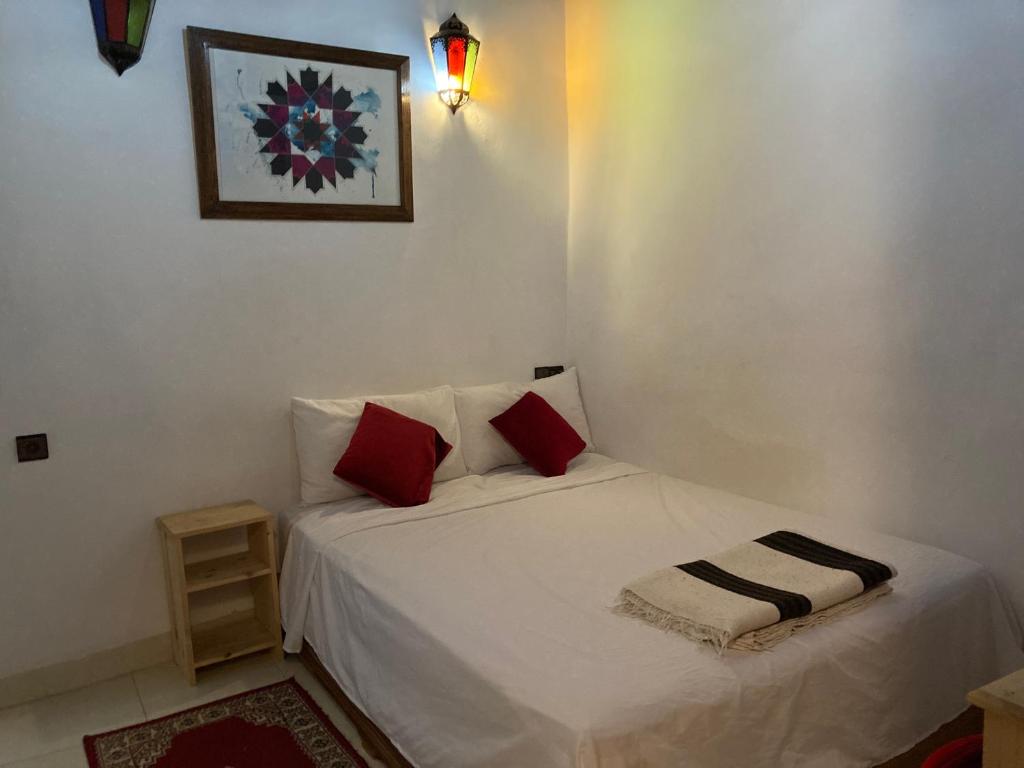 a small bedroom with a white bed with red pillows at Dar Zin in Fez