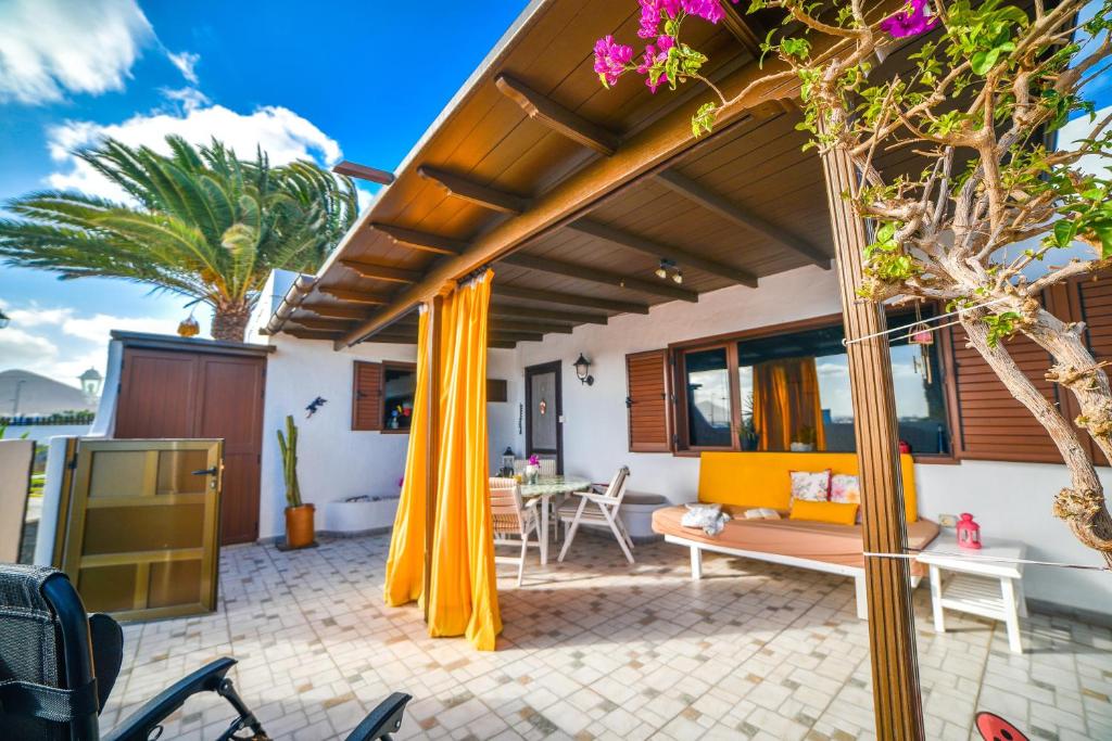 un patio al aire libre con cortinas amarillas y una mesa en Casa Tamai, ideal para familias en el centro de la isla en Teguise