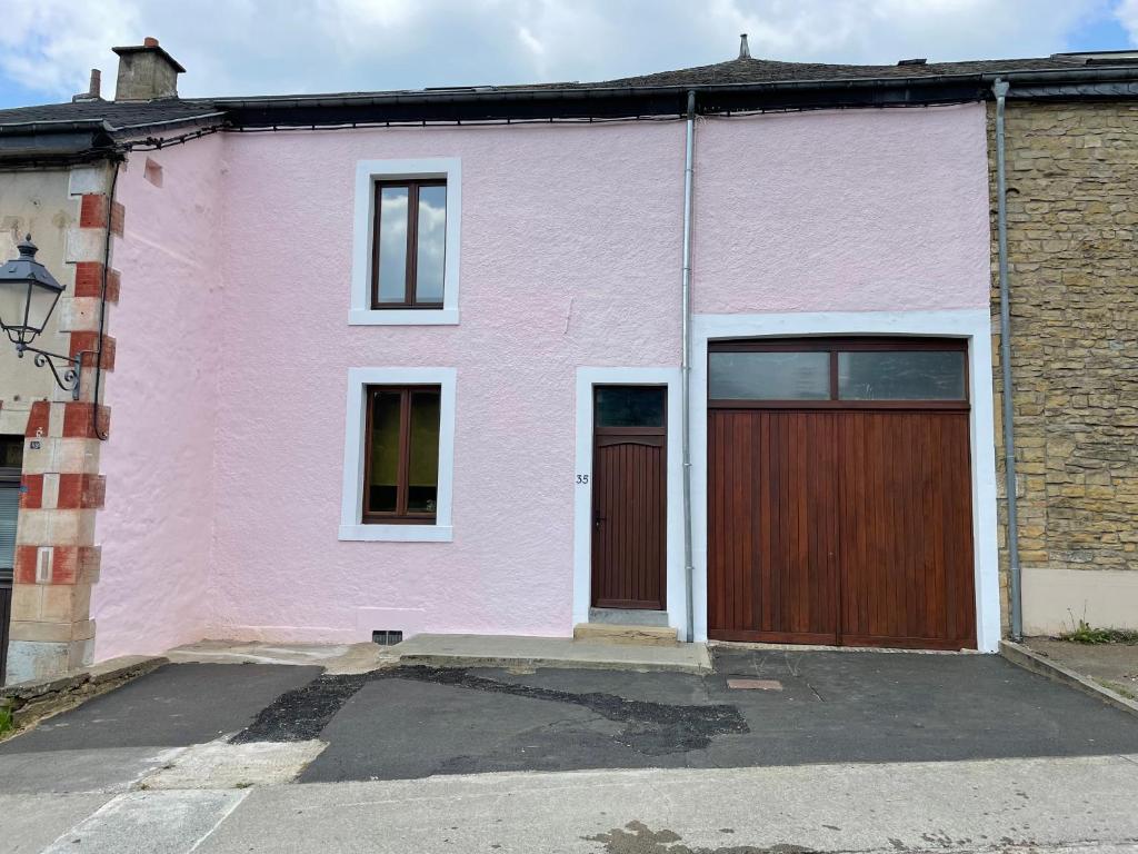 a pink house with a brown door on a street at la vie en rose in Muno