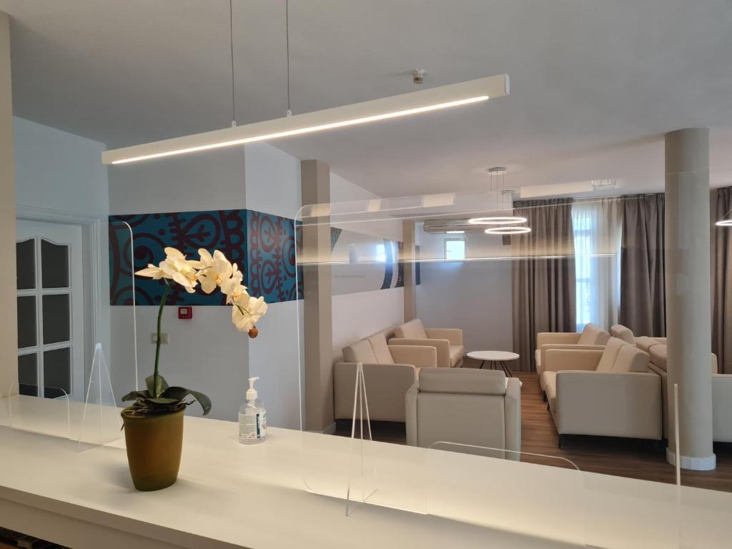 una sala de estar con muebles blancos y un jarrón de flores en Hotel Balneario Fuentes del Trampal, en Carmonita