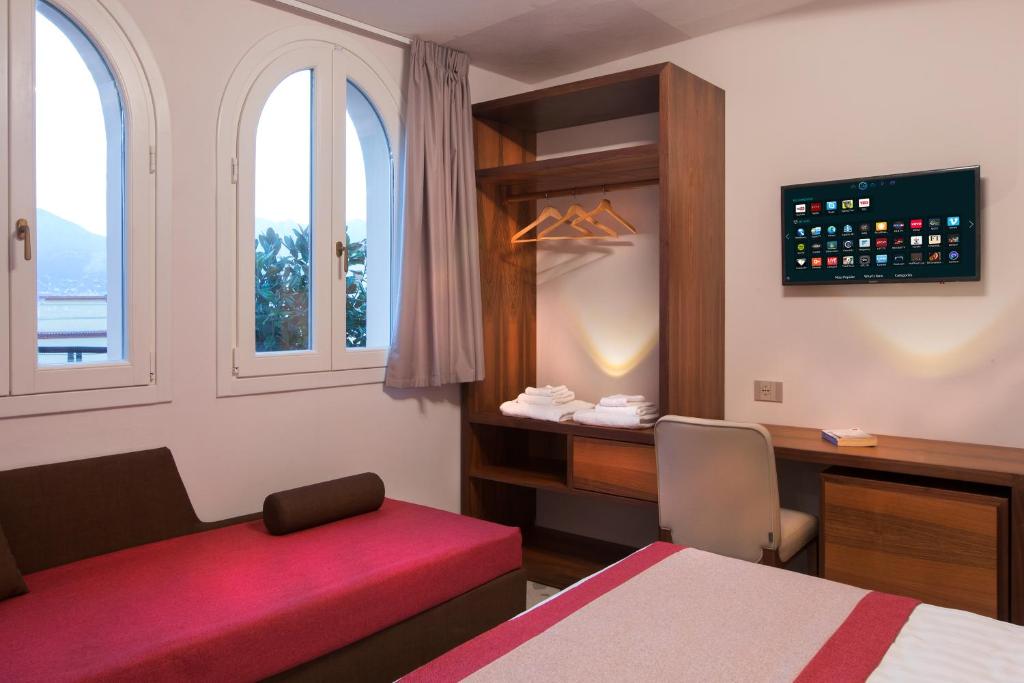 a room with a bed and a desk and two windows at Dimora del Leone Gaeta in Gaeta