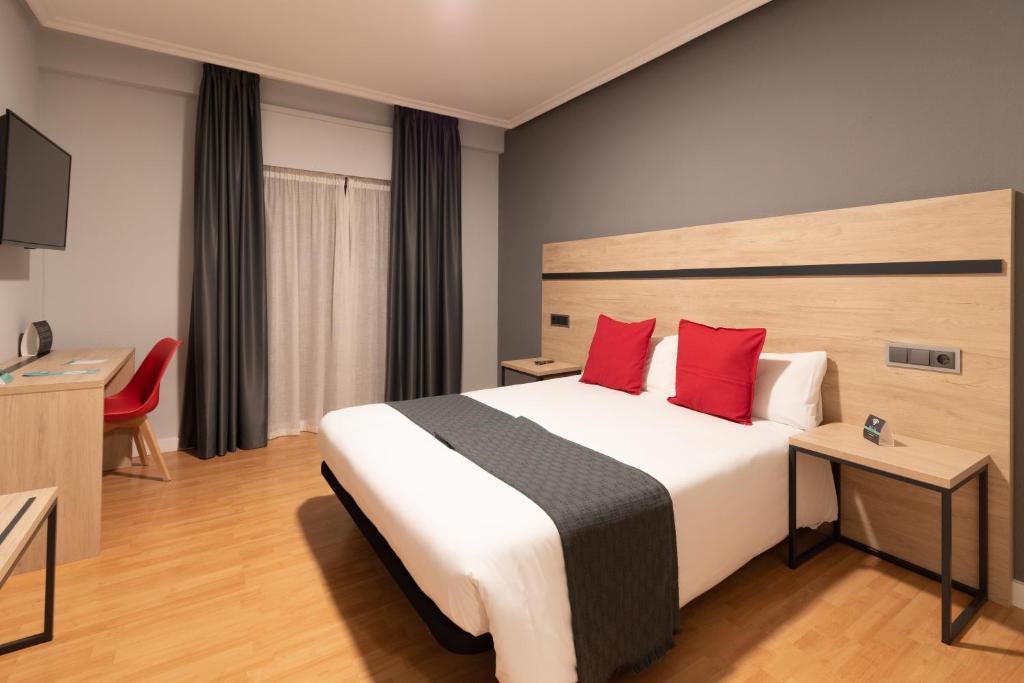 una habitación de hotel con una cama grande con almohadas rojas en Alda Centro Zaragoza, en Zaragoza