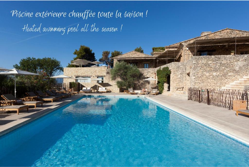 une grande piscine d'eau bleue en face d'un bâtiment dans l'établissement Mas des Herbes Blanches Hôtel & Spa – Relais & Châteaux, à Joucas