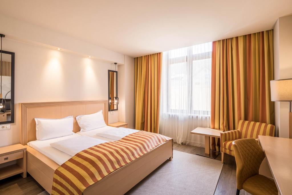 een hotelkamer met een bed en een bureau bij Hotel Rogge in Reşiţa