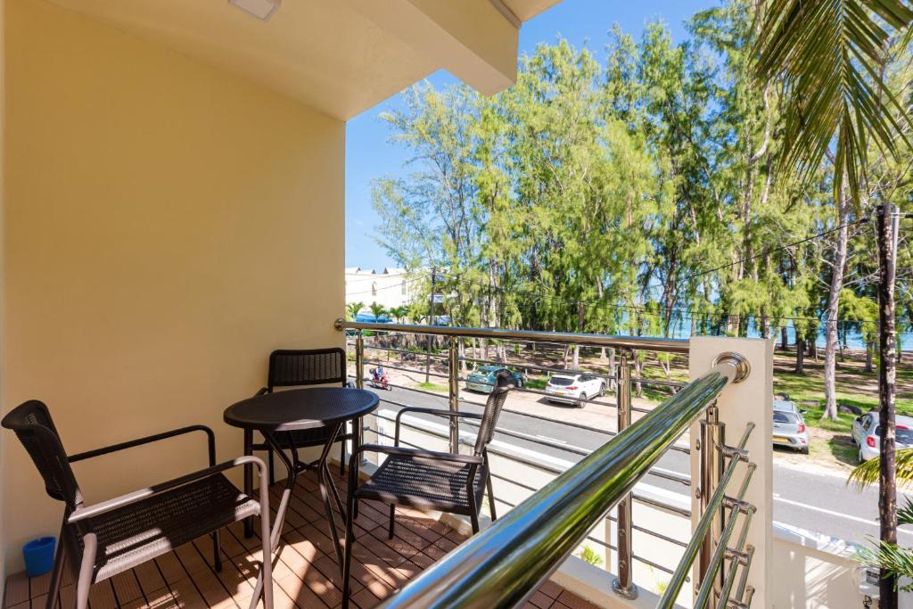 a balcony with chairs and a table and a street at C-view Apartments in Flic-en-Flac