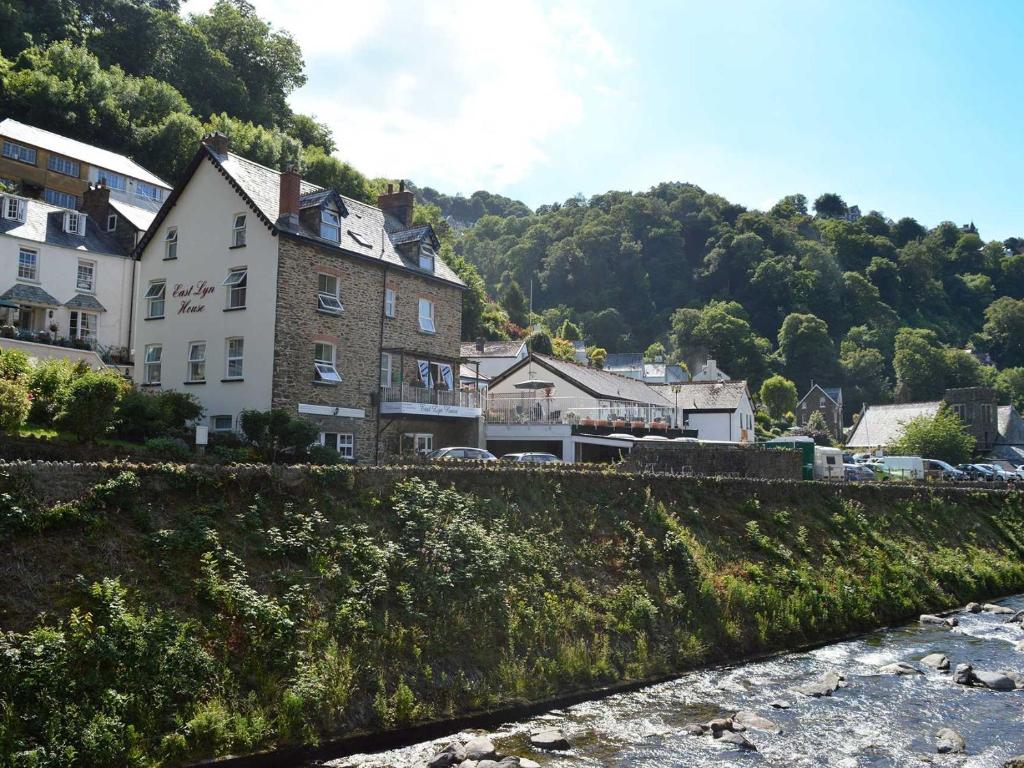 een groep gebouwen op een heuvel naast een rivier bij East Lyn House in Lynmouth