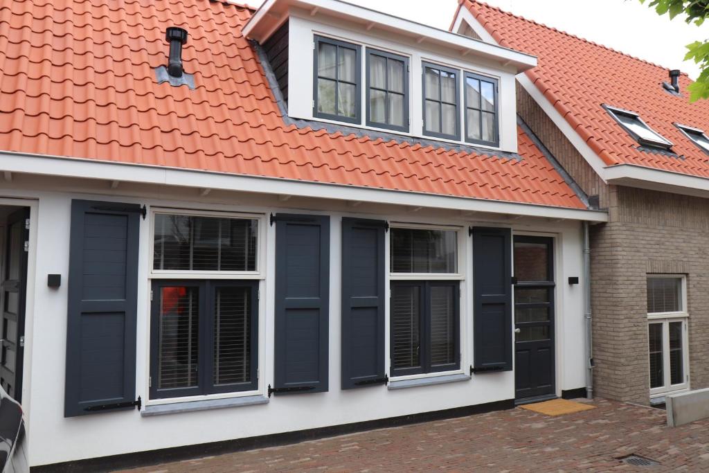 a house with an orange roof and black shutters at Guesthouse Bonniehofje in Zandvoort