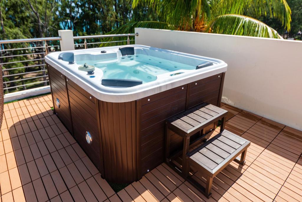 a jacuzzi tub on a deck with a bench at C-view Apartments in Flic-en-Flac