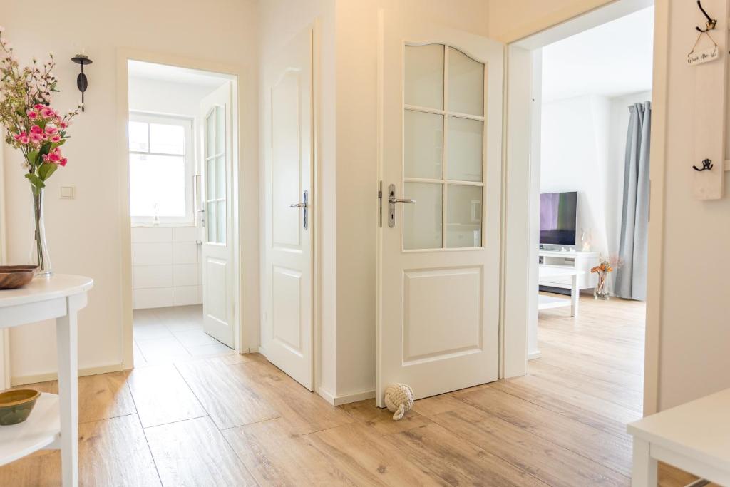 pasillo con puerta blanca y suelo de madera en Ferienwohnung F5, en Graal-Müritz