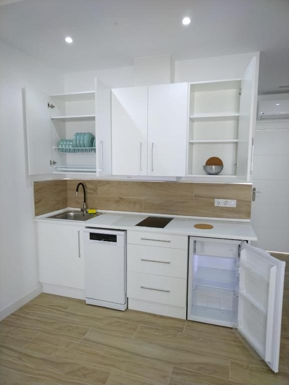 Biała kuchnia z białymi szafkami i zlewem w obiekcie CASTRO Suites Osuna w mieście Osuna