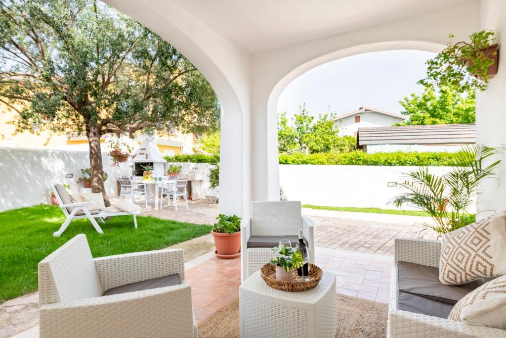 an outdoor patio with white furniture and a yard at casa perla marina in Lotzorai