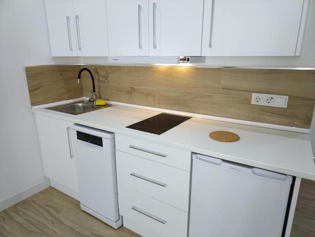a white kitchen with white cabinets and a sink at CASTRO Suites Osuna in Osuna