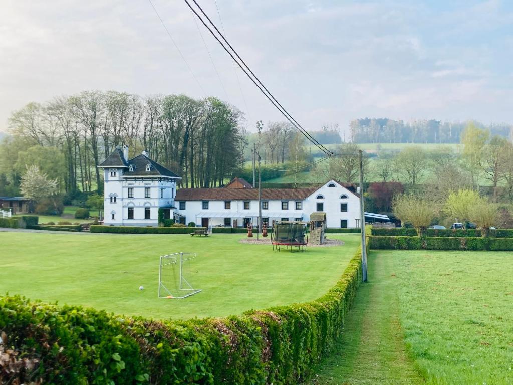 een groot wit huis met een veld met een voetbal bij De Molenhoeve in Voeren