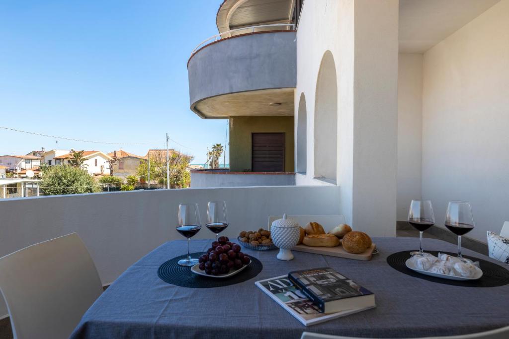 a table with wine glasses and food on a balcony at Al Castello - Etna e Mare in Agnone Bagni