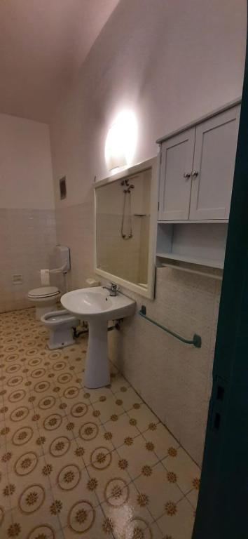 łazienka z 2 toaletami, umywalką i lustrem w obiekcie Casa Vacanze Else w mieście Lazzaro